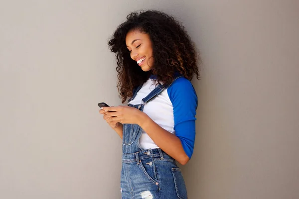 Retrato Lateral Joven Afroamericana Sonriente Mirando Teléfono Inteligente Contra Fondo — Foto de Stock