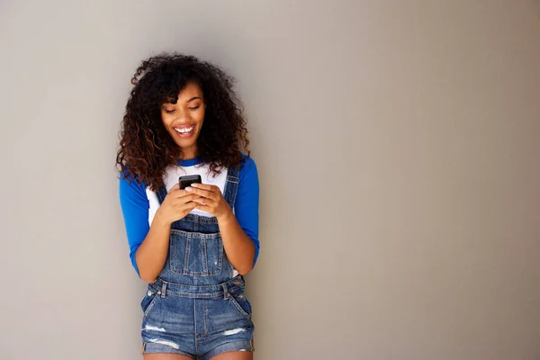 横向肖像美丽的年轻黑人女子看着智能手机与灰色背景 — 图库照片