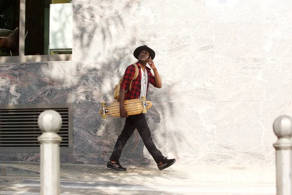 非洲人的全身肖像用滑板走在外面使用手机 — 图库照片