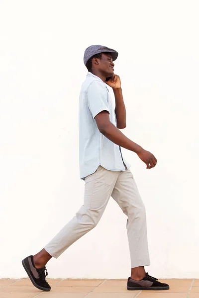 電話で話している外を歩く若いアフリカ人のフルボディ側面の肖像画 — ストック写真