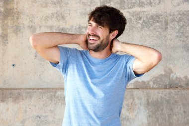 Ellerini başının arkasında ile gülümseyen mutlu genç adam portresi