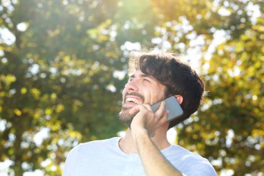 Smartphone açık havada üzerinde konuşmak mutlu genç adam portresi kapatın