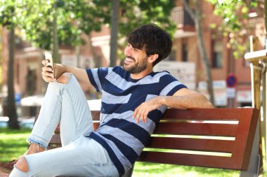 Park içinde hareket eden telefon ile gülümseyen genç adam portresi