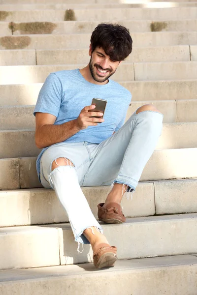 Portret Van Vriendelijke Jongeman Zittend Stappen Kijken Naar Mobiele Telefoon — Stockfoto