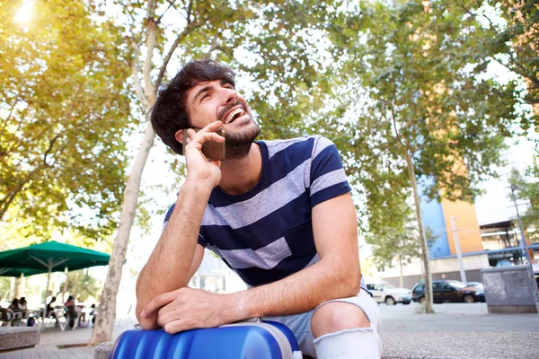 Retrato Joven Viajero Sentado Afuera Con Una Bolsa Hablando Por —  Fotos de Stock