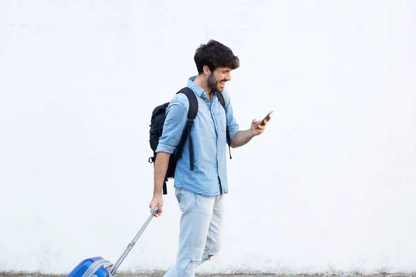 Retrato Lateral Hombre Feliz Caminando Con Smartphone Maleta Por Pared Imagen De Stock