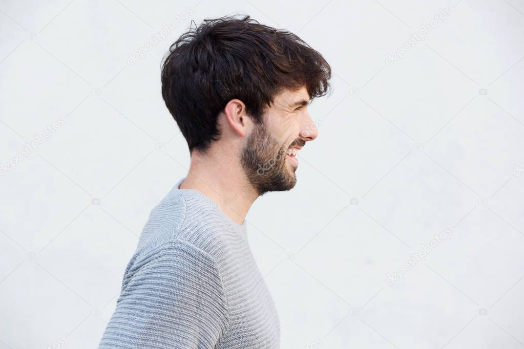 Close up side portrait of happy young man with beard against white background