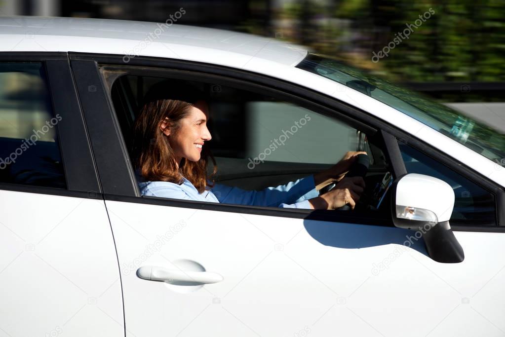 Side portrait of smiling older woman driving car 