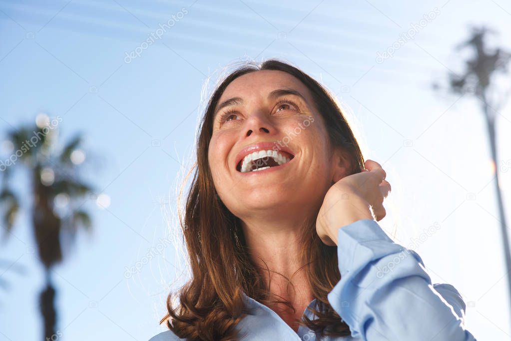 Close up portrait of happy  woman laughing Wirth hand in hair outside