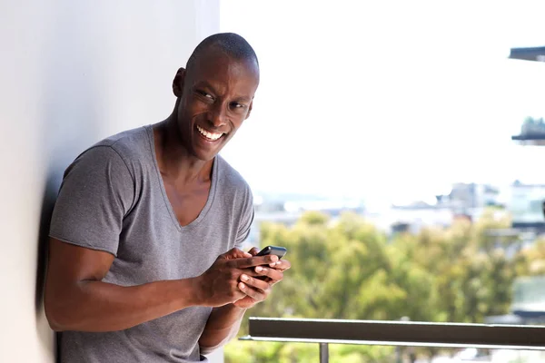Porträtt Lycklig Afroamerikanska Man Lutad Mot Väggen Med Mobiltelefon — Stockfoto