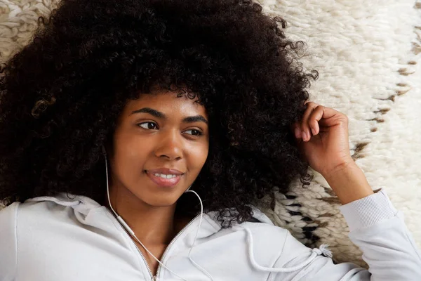 長い巻き毛とイヤホンで音楽を聞く美しいアフリカ系アメリカ人少女の肖像画を閉じる — ストック写真