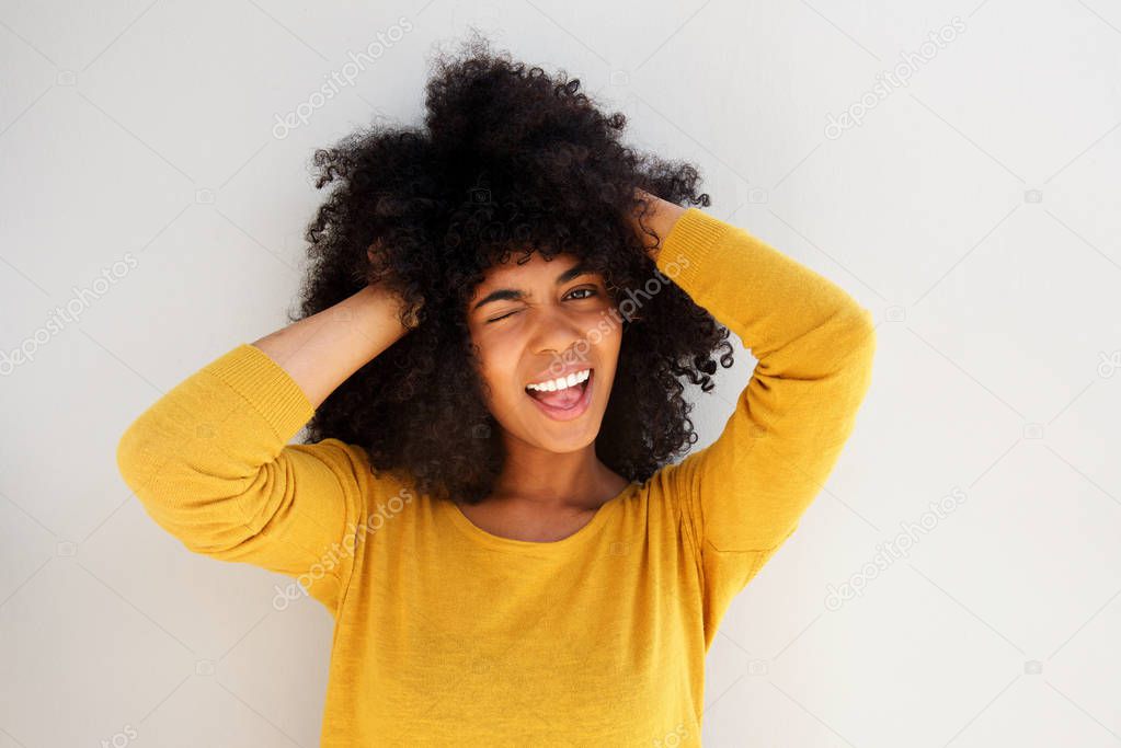 Close up portrait of young african girl laughing and winking against white background