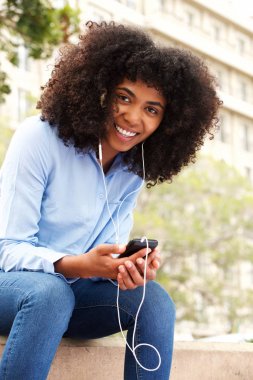Akıllı telefon dış dinleme müzik rahatlatıcı neşeli genç Afro-Amerikan kadın portresi