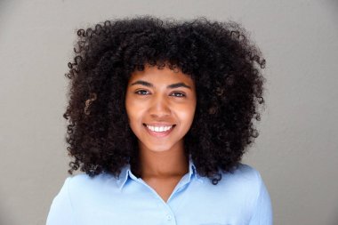 Gri arka planı gülümseyen güzel genç Afro-Amerikan kadın portresi kapatın