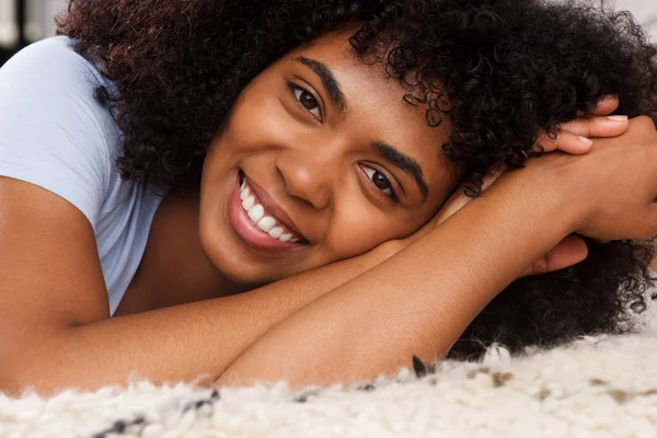 幸せな若いアフリカ系アメリカ人女性の床に横になっていると笑顔の肖像画間近します — ストック写真