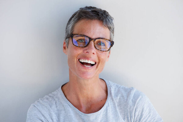 Close up portrait of attractive older woman smiling with glasses against white background
