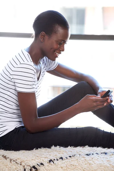 Sida Porträtt Glad Ung Svart Kvinna Med Mobiltelefon Genom Fönster — Stockfoto