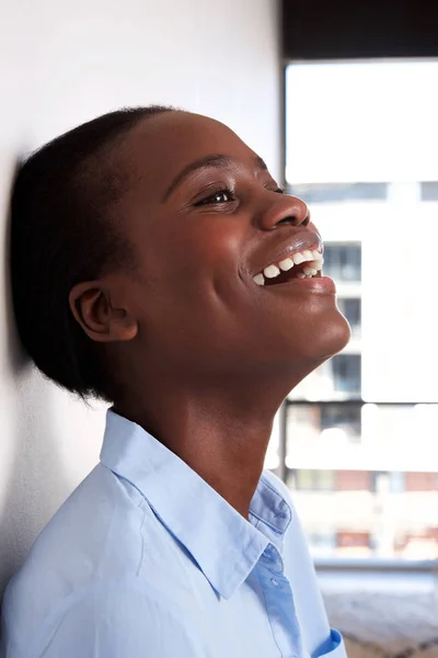 Close up portrait of happy black woman leaning against wall and smiling