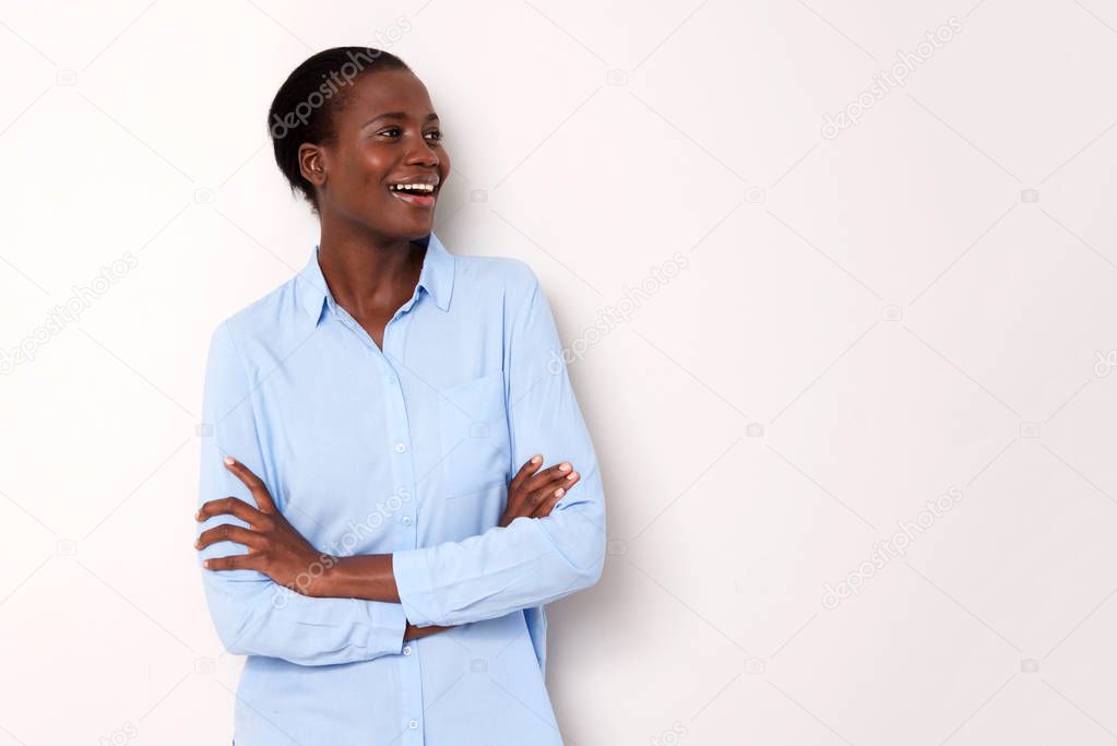 Portrait of smiling african woman standing with arms crossed and looking away on white background