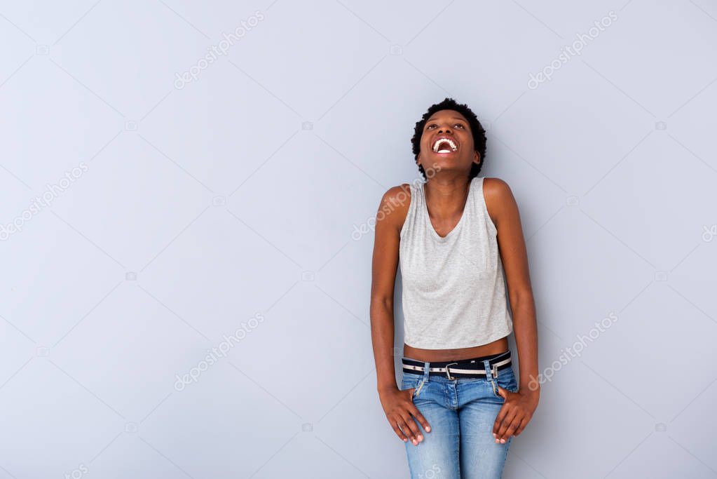 Portrait of happy african woman laughing by gray wall with copy space