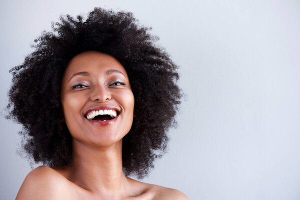 Close up portrait of attractive young woman with naked shoulders laughing on gray background