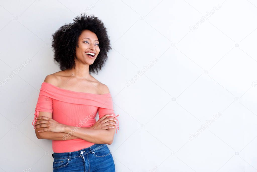 Portrait of attractive black woman smiling with arms crossed against white background