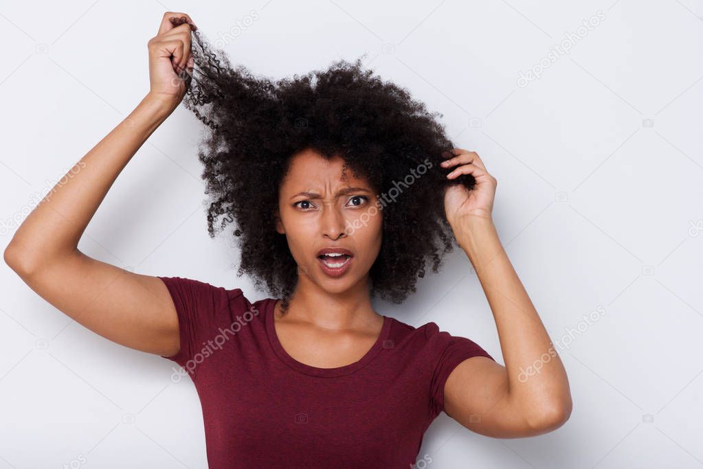 Close up portrait of young african woman pulling bad curly hair and looking worried