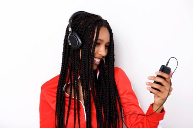 Cep telefonu ve beyaz arka plan üzerinde kulaklık ile müzik dinleme serin genç Afrikalı kadın portresi kapatın