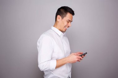 Orta gülümseyen portresi yaşlı adam gri arka plan üzerinde cep telefonuna kısa mesaj okuma