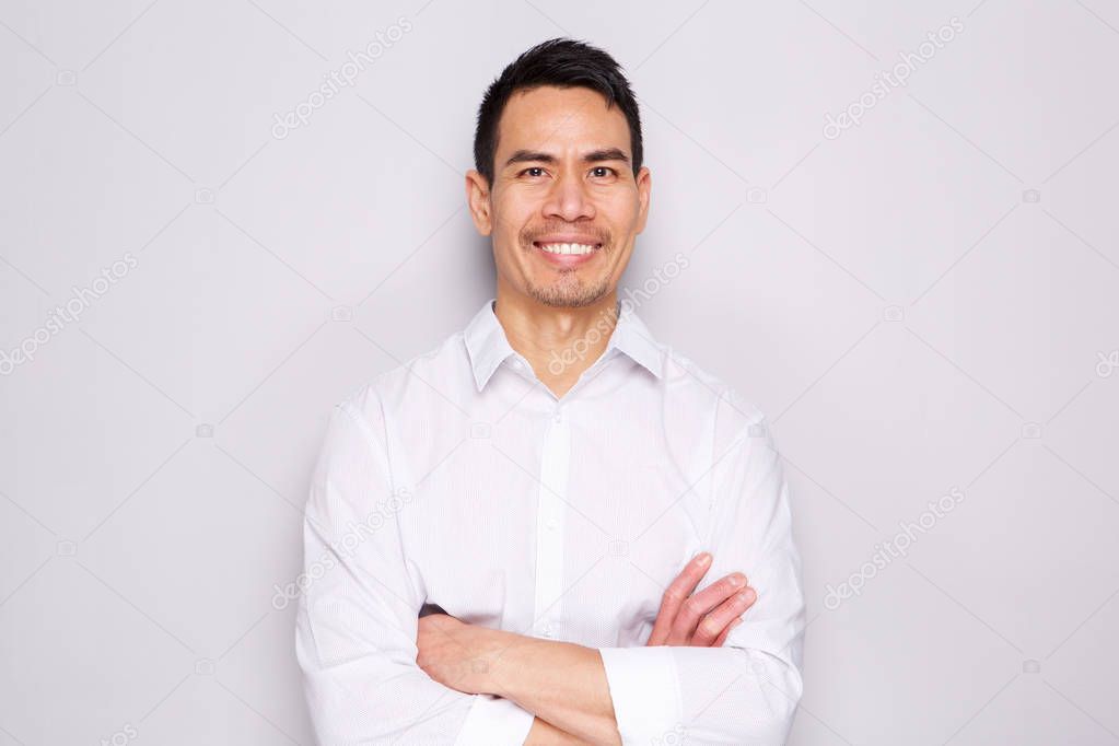 Close up portrait of happy middle aged asian man standing with his arms crossed against gray background