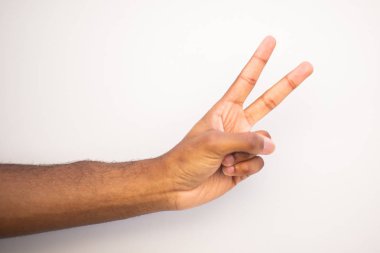 Beyaz arka planı işaret eden iki parmağıyla Afro-Amerikan erkek kolunu kapat.