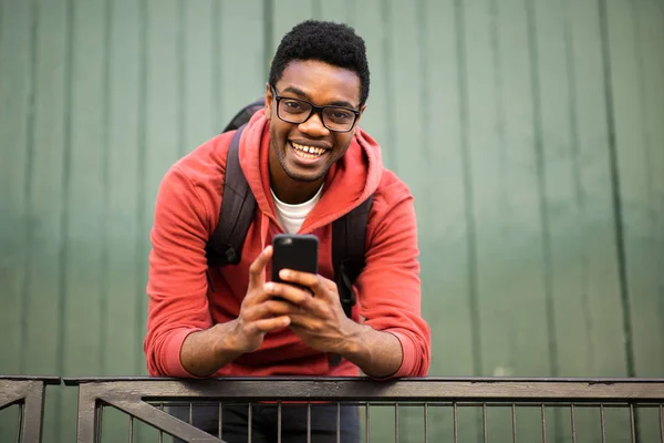 肖像画笑顔若いですアフリカ系アメリカ人男性とともに眼鏡と携帯電話 — ストック写真