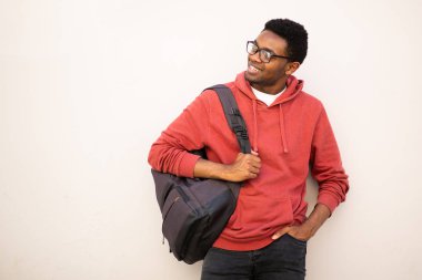 Gözlüklü, çantalı, beyaz arka plana bakan Afro-Amerikan genç bir portre. 