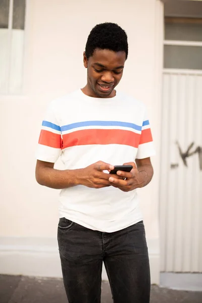 若いアフリカ系アメリカ人男性の携帯電話を外で見ている — ストック写真