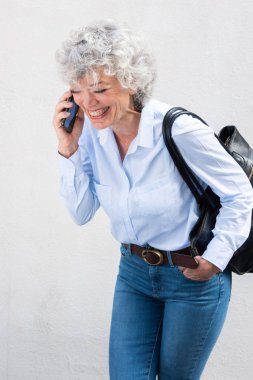 Yaşlı kadın portresi cep telefonuyla gülüyor ve konuşuyor.