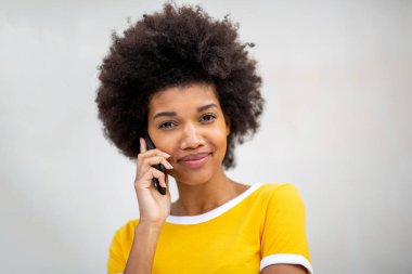 Güzel siyahi bir kadının beyaz arka planda cep telefonuyla konuştuğu portreyi yakından çek. 