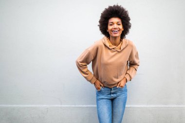 Gri arka planda afro saçlı, gülümseyen güzel siyah kadın portresi.