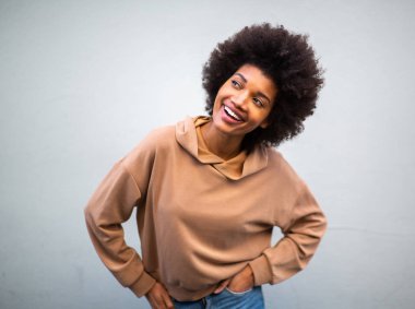 Gri arka planda afro saçlı, gülümseyen güzel siyah kadın portresi.