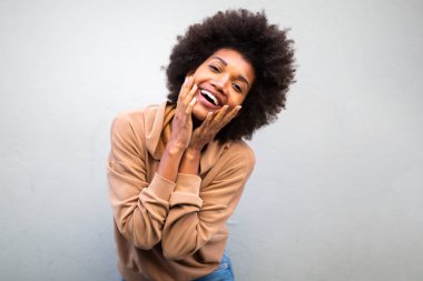 Güzel siyah gülümseyen kadın portresi afro saçlı ve yüzünde gri duvar olan.