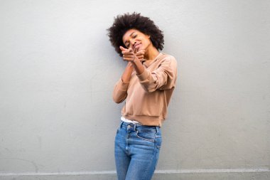 Genç Afro-Amerikan kadın portresi gri arka planla işaret ediyor. 