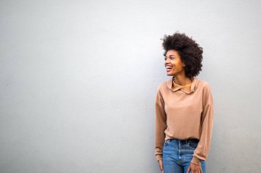 Portre mutlu genç çekici Afrikalı Amerikalı kadın gri arka planda gülüyor.