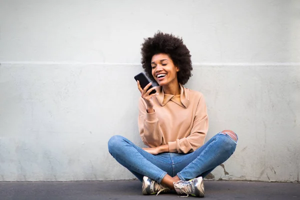 幸せな若いアフリカ系アメリカ人女性の肖像携帯電話で床に座って — ストック写真