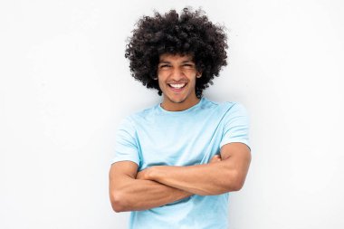 Afro saçlı ve kollarını kavuşturmuş beyaz arka planda gülümseyen yakışıklı genç bir adamın portresi.