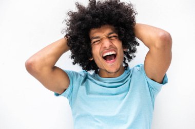 Beyaz arka planda elleri başının arkasında bağıran afro saçlı yakışıklı genç bir adam portresi.