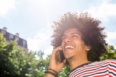Kuzey Afrikalı genç adamın cep telefonuyla konuşan ve gülen portresini yakından çek.
