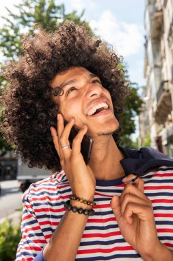 Kapalı kapılar ardında cep telefonuyla konuşan afro saçlı, mutlu, genç bir Arap 'ın portresi.
