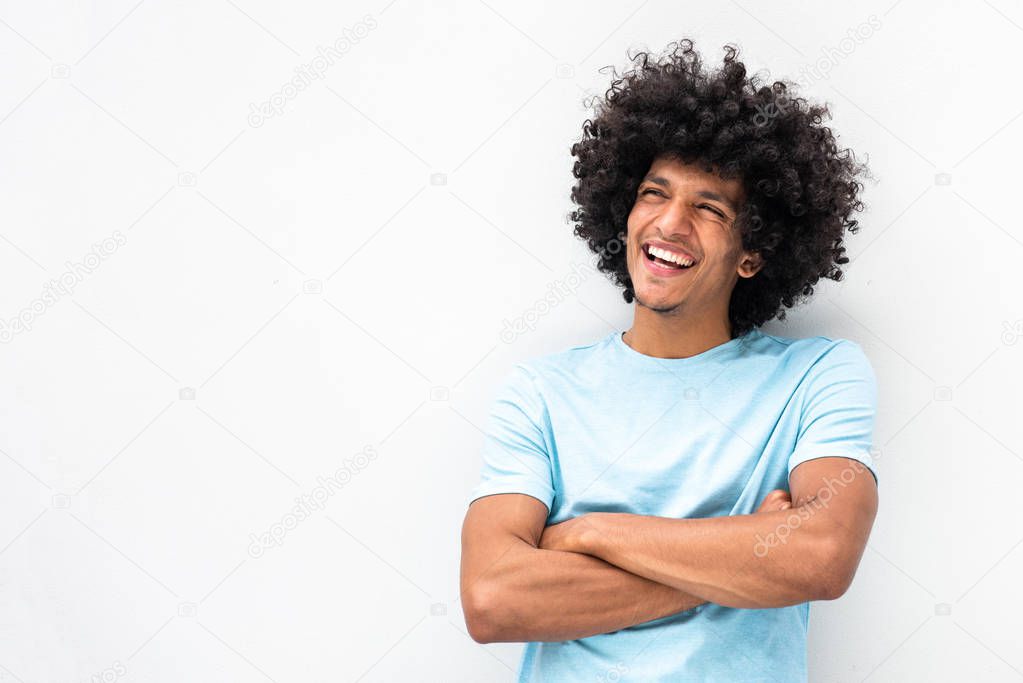 Portrait smiling young man with afro hair and arms crossed smiling by white background