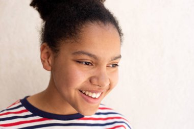 Beyaz arka planda gülümseyen Afrikalı Amerikalı kızın yakın portresi.