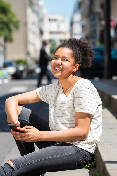 Porträtt Skrattar Ung Afrikansk Amerikansk Flicka Sitter Utanför Staden Håller — Stockfoto