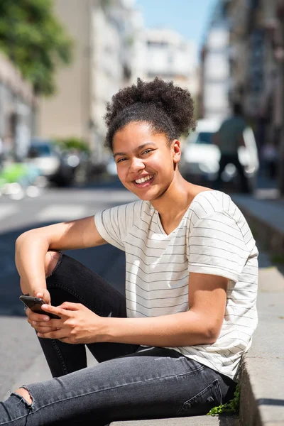 Retrato Joven Afroamericana Feliz Sentada Afuera Ciudad Sosteniendo Teléfono Móvil — Foto de Stock